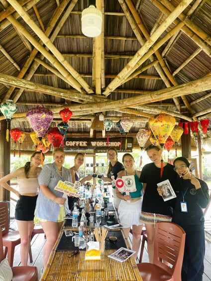 A group of people at a coffee workshop with bamboo ceilings and hanging lanterns. 5
