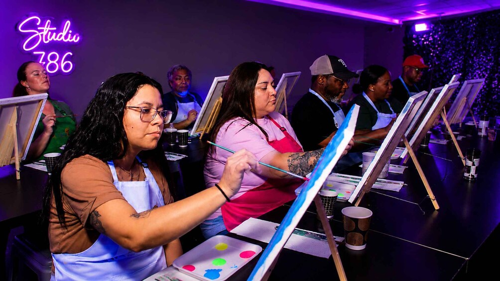 People painting in a studio with easels and paint palettes. 2