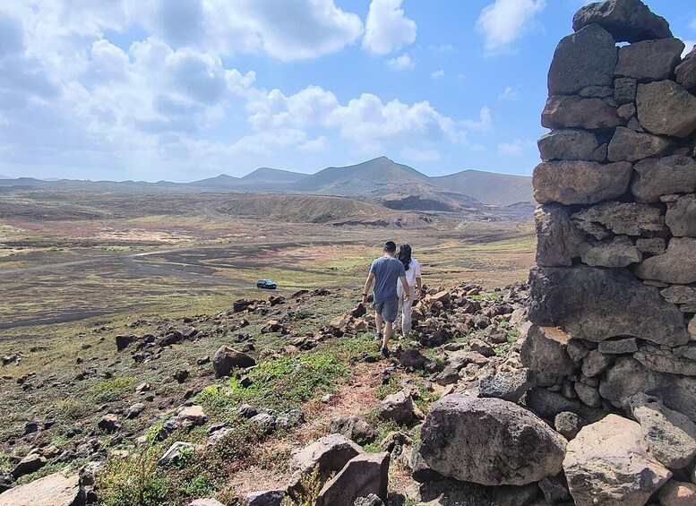A rocky landscape with a stone wall and distant mountains under a clear sky. 3