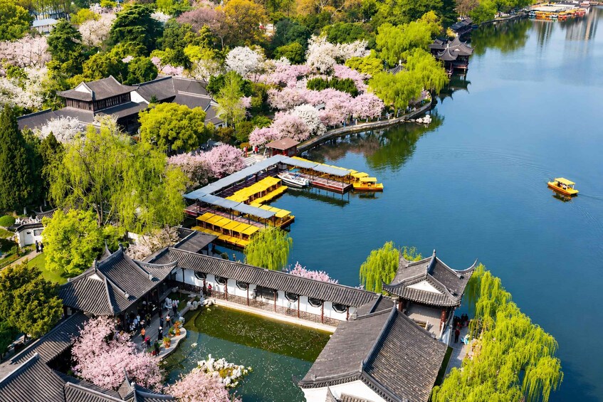 A traditional Chinese garden with water features, cherry blossoms, and a boat dock. 5