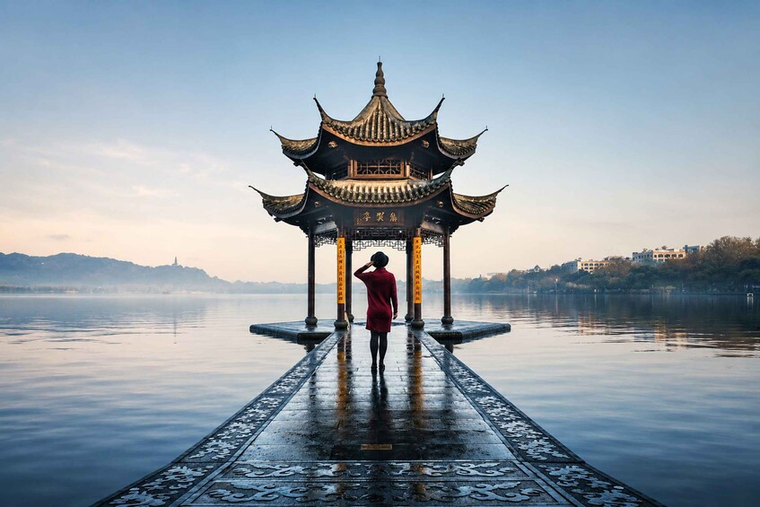 A person standing on a bridge with a traditional pavilion in the background. 2