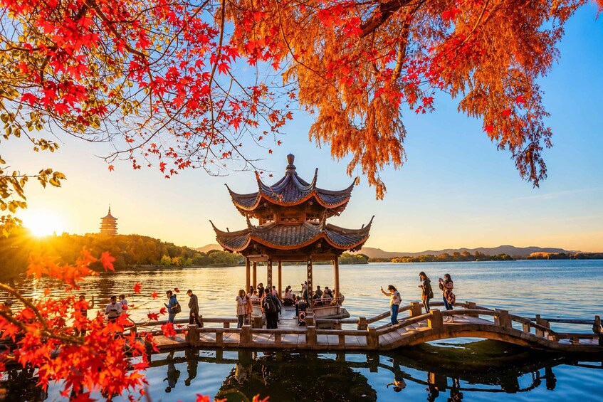 A traditional pavilion by a lake with people around it. 3