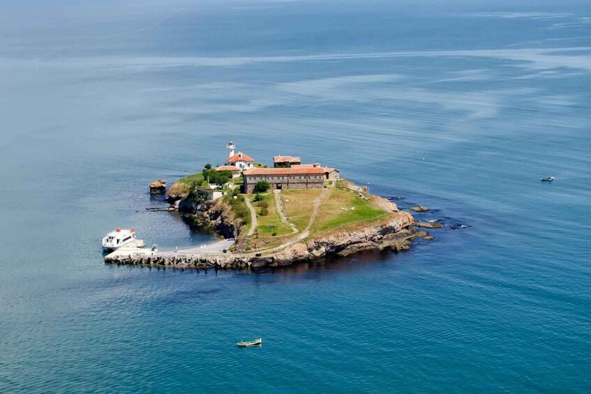 An island with a lighthouse, a fort, and a small boat. 3