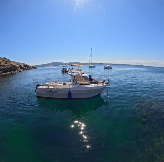 A boat named 'NINA-1' anchored in clear blue waters with other boats in the background. 1