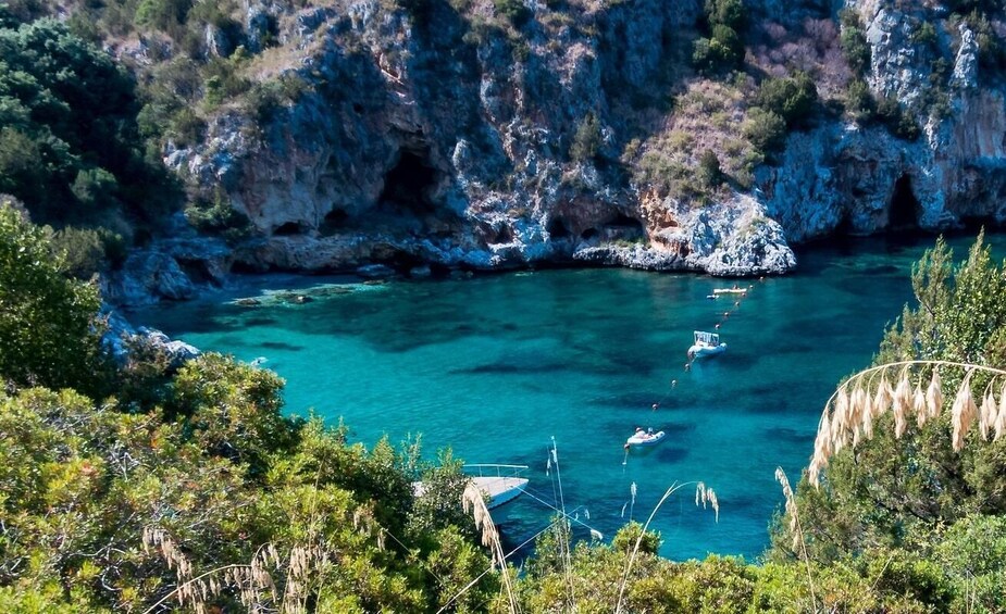 A coastal landscape with clear turquoise waters, rocky cliffs, and sparse vegetation. 2