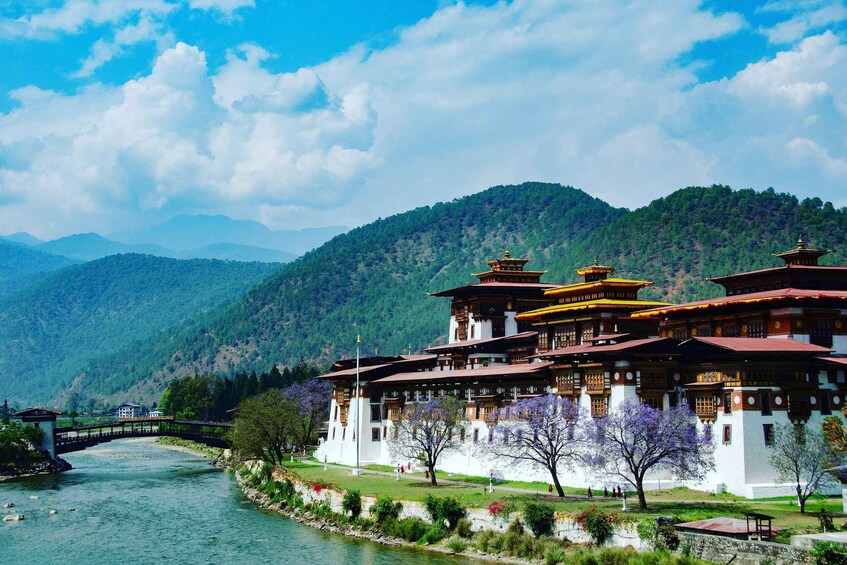 A traditional multi-tiered building with a river in the foreground and mountains in the background. 4