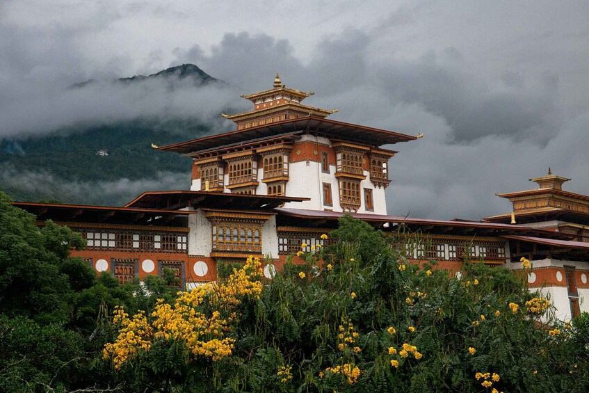 A traditional multi-tiered building with ornate architecture, surrounded by lush greenery and mountains in the background. 2
