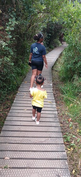 Two people walking on a paved path surrounded by greenery. 5