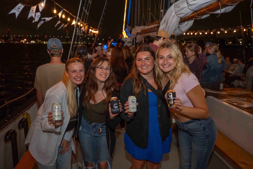 A group of people on a boat with string lights and a cityscape in the background. 5
