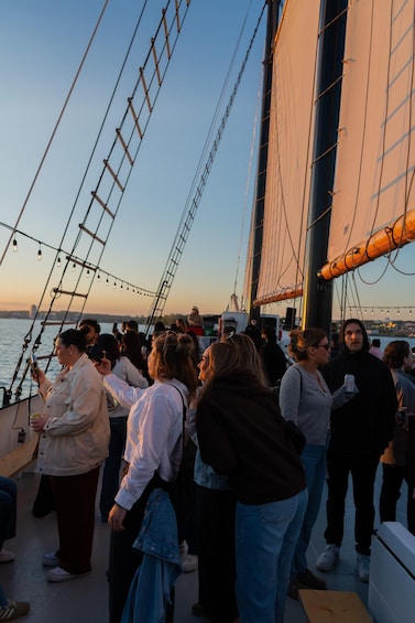 A group of people on a boat with sails, docked near a body of water. 4