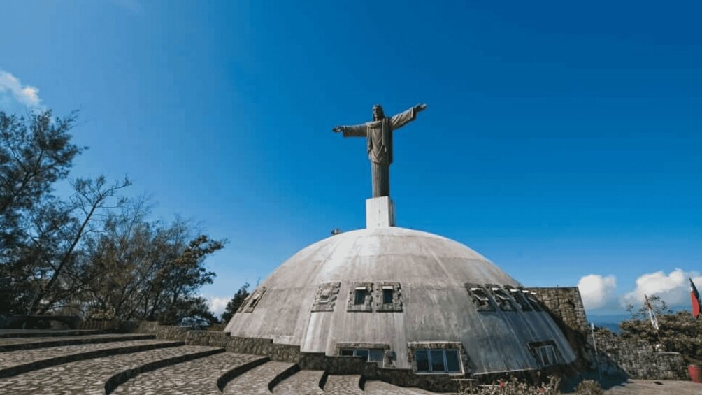 A large statue atop a dome structure, surrounded by stone steps and trees. 4