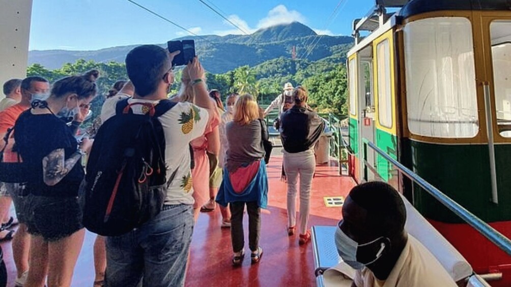 A group of people on a tram with a mountainous landscape in the background. 1