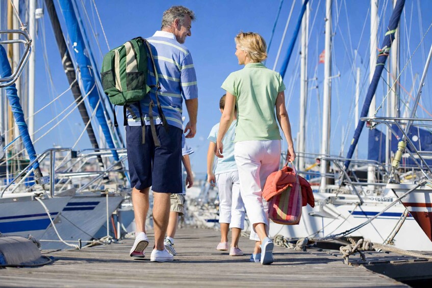 A couple walking on a wooden dock with boats in the background. 1