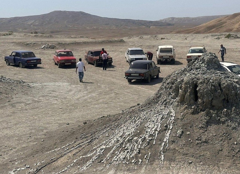 A group of cars parked in a barren landscape with mountains in the background. 5