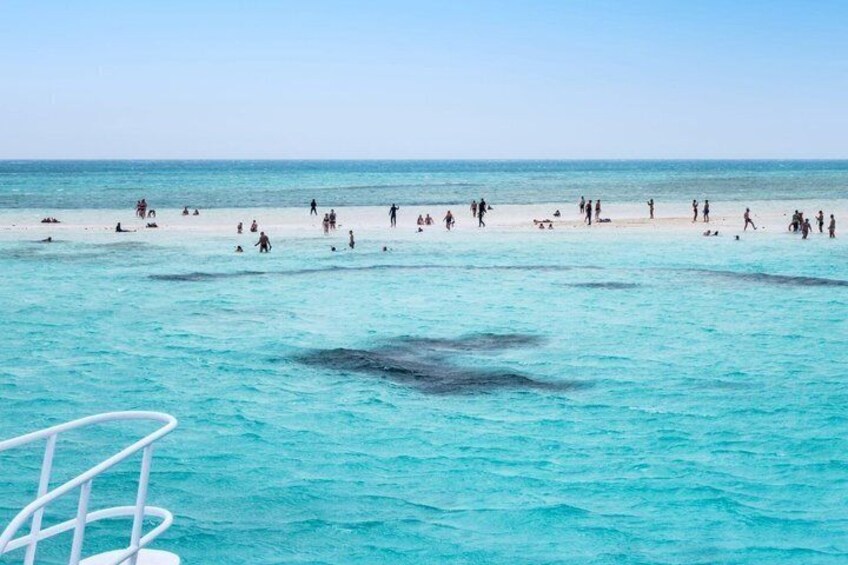 A beach with people swimming and walking on the sand. 4