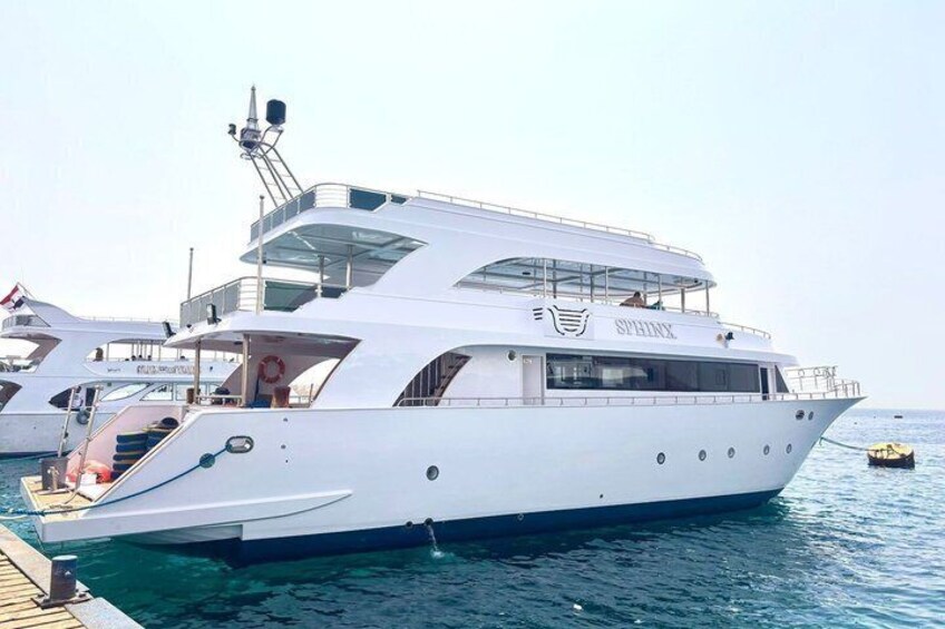 A large white yacht docked at a marina with clear blue water. 1