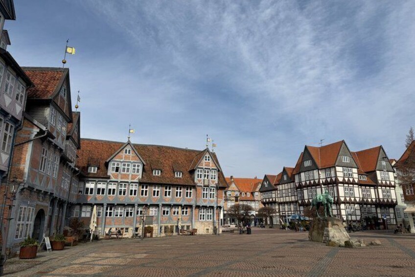 A historic European town square with traditional half-timbered buildings and a cobblestone pavement. 1