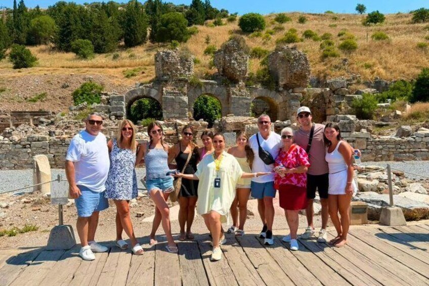 A group of people standing on a wooden deck with ancient ruins in the background. 4
