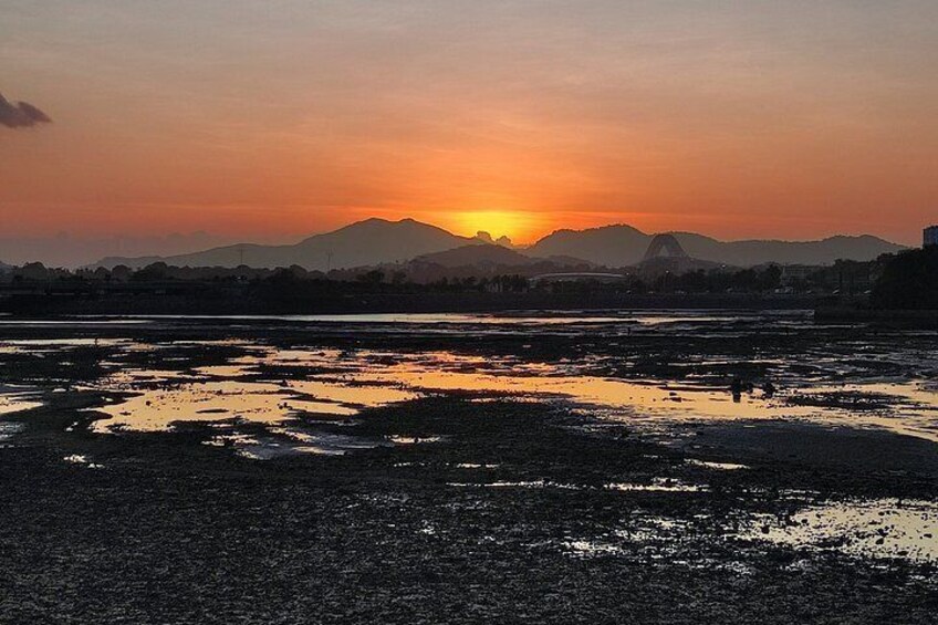 A sunset over a flooded landscape with mountains in the background. 2