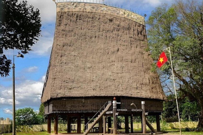 A thatched-roof structure with a flag, surrounded by trees and a clear sky. 4