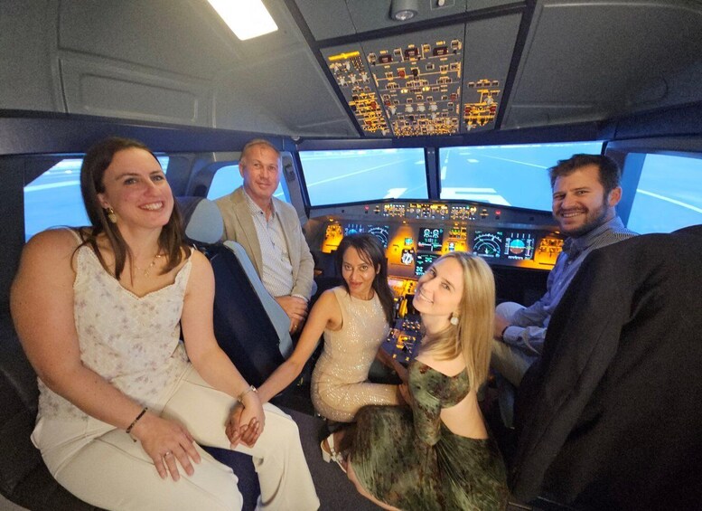 A group of people inside a cockpit with multiple screens and controls. 4