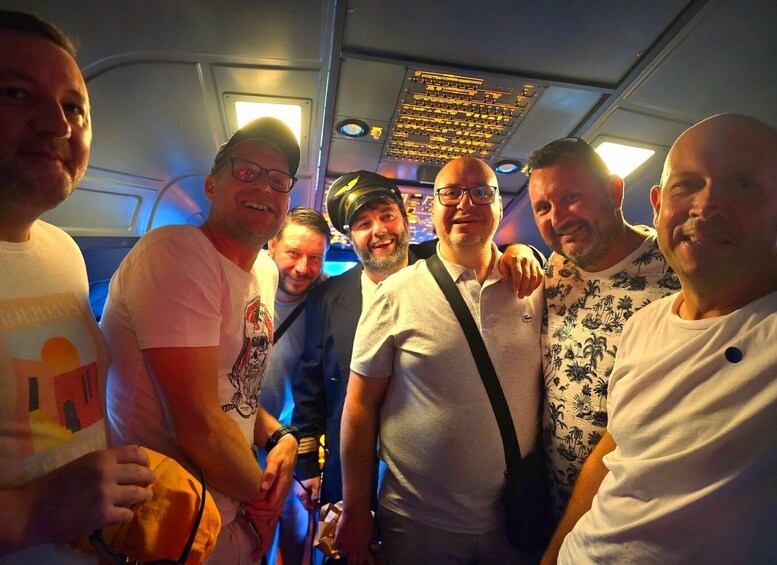 A group of people on a boat with a control panel and overhead lights. 3