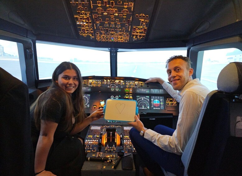 A cockpit with multiple control panels and a person holding a sign with a heart drawing. 2