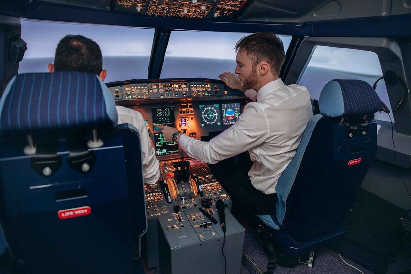 Two pilots in a cockpit with multiple control panels and a view of the sky. 1