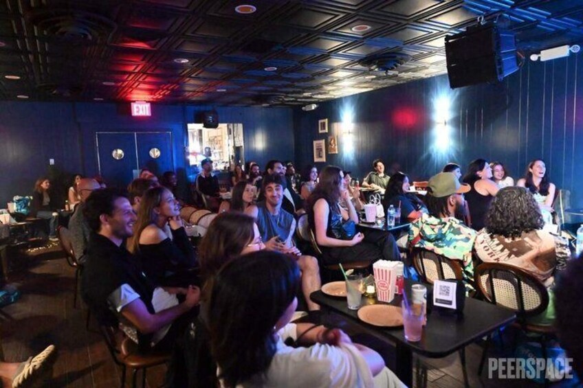 A crowded indoor venue with tables, chairs, and people engaged in social activities. 2