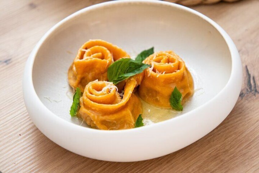 A white plate with three rolled pasta shapes, garnished with a mint leaf. 2