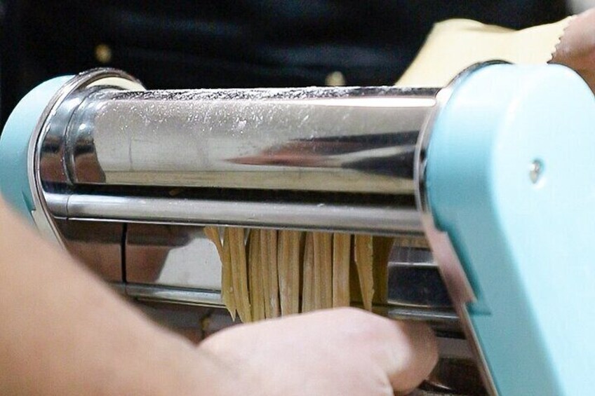 A person using a pasta machine to roll out dough. 3