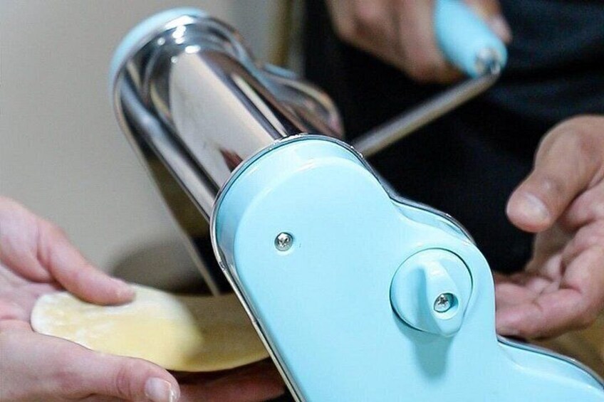 A person using a light blue kitchen tool to cut dough. 5