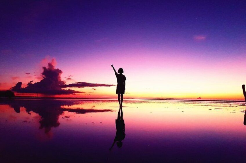 A person standing on a reflective surface at sunset with a vibrant sky. 5