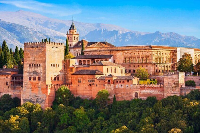 A historic castle with a tower, surrounded by lush greenery and mountains in the background. 1