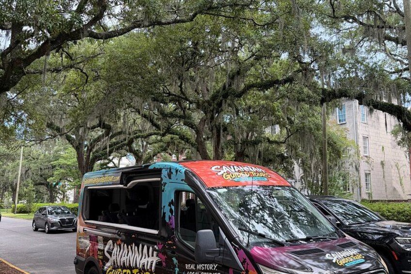 A food truck parked on a street with large trees and a building in the background. 3