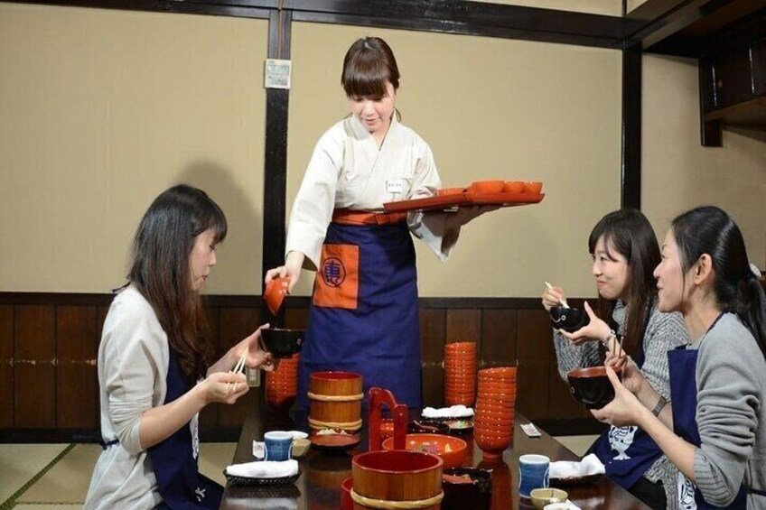 A person serving food to a group of people at a table with various dishes and utensils. 2