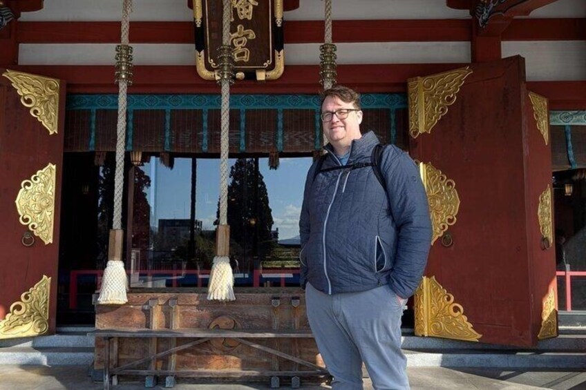 A person standing in front of a traditional building with ornate golden decorations and a wooden structure. 4