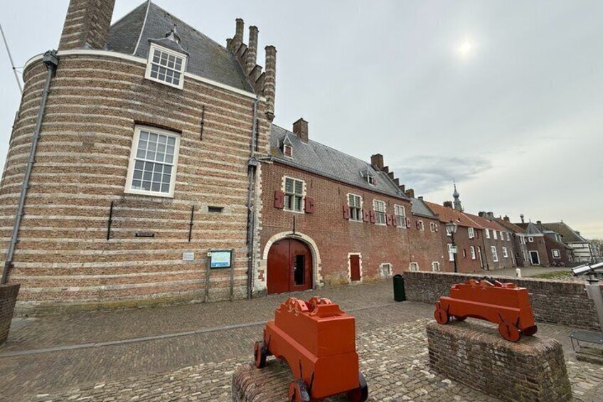 A historic brick building with a round tower, a red door, and a cobblestone street. 3