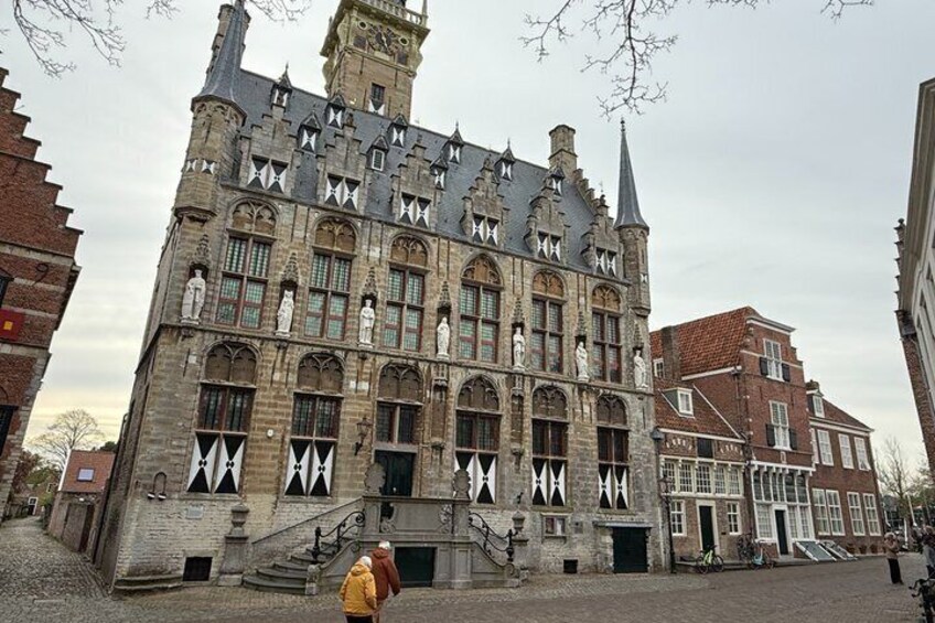 A historic building with a steep roof, multiple windows, and a prominent tower. 5
