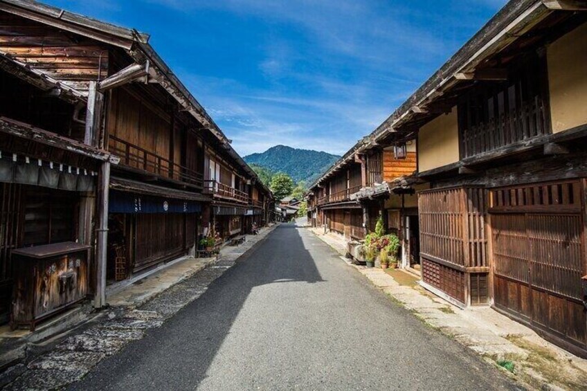 A street lined with traditional wooden buildings, a clear sky, and mountains in the distance. 3
