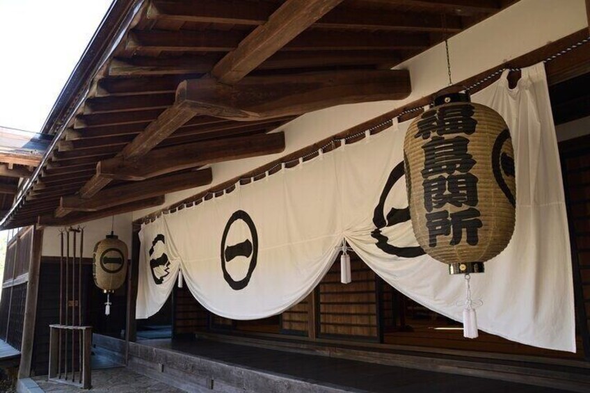 A traditional Japanese building with wooden beams, white curtains, and hanging lanterns. 5
