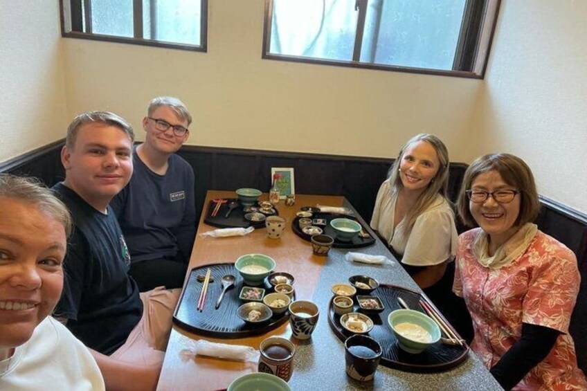 A group of people seated around a table with various dishes and drinks. 3