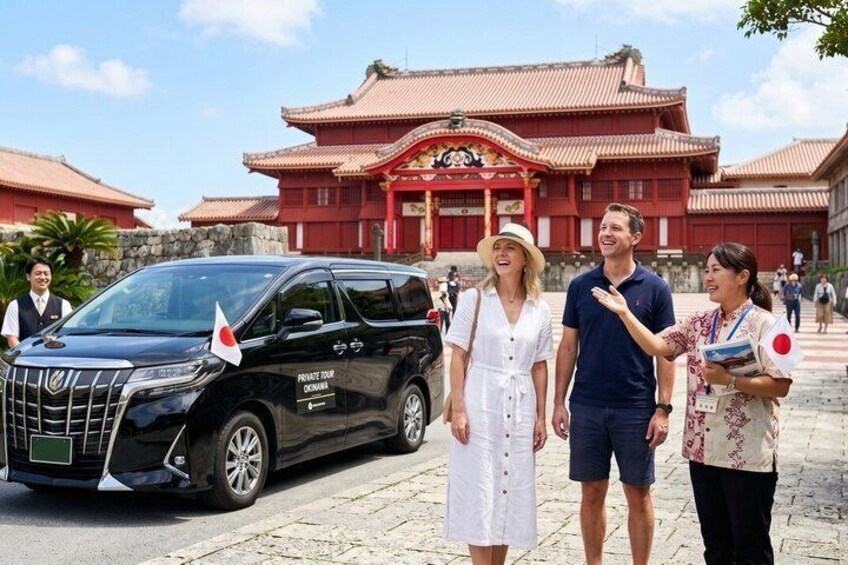 A black SUV with a flag, a traditional building with red roofs, and people standing in front. 1