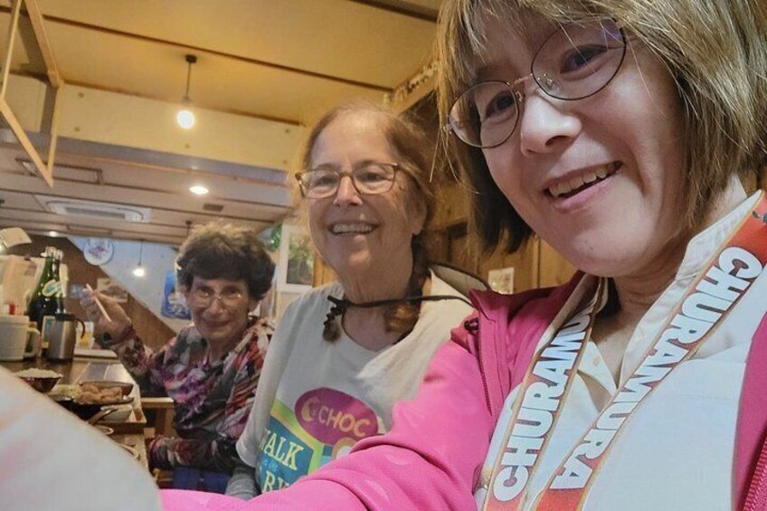 Two people wearing lanyards with 'CHURCH WALK' on them, in a room with wooden beams and a table with items on it. 2