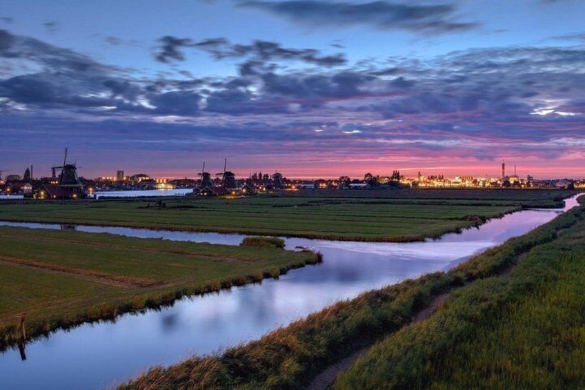 A river meandering through agricultural fields at dusk with industrial structures in the background. 4