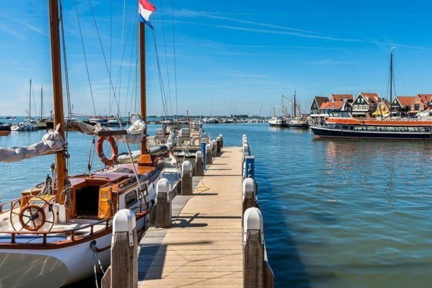 A wooden pier with boats docked, a flag, and a building with a red roof in the background. 3