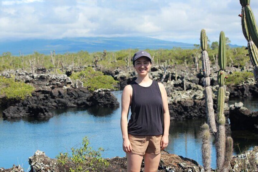 A person standing near a body of water with cacti and rocky terrain in the background. 3