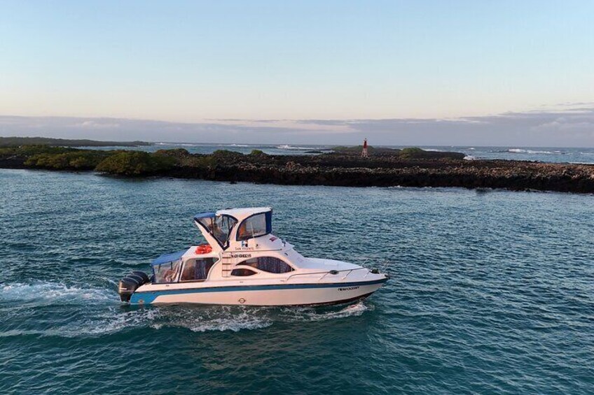 A speedboat on a body of water with a rocky shoreline and a lighthouse in the distance. 5