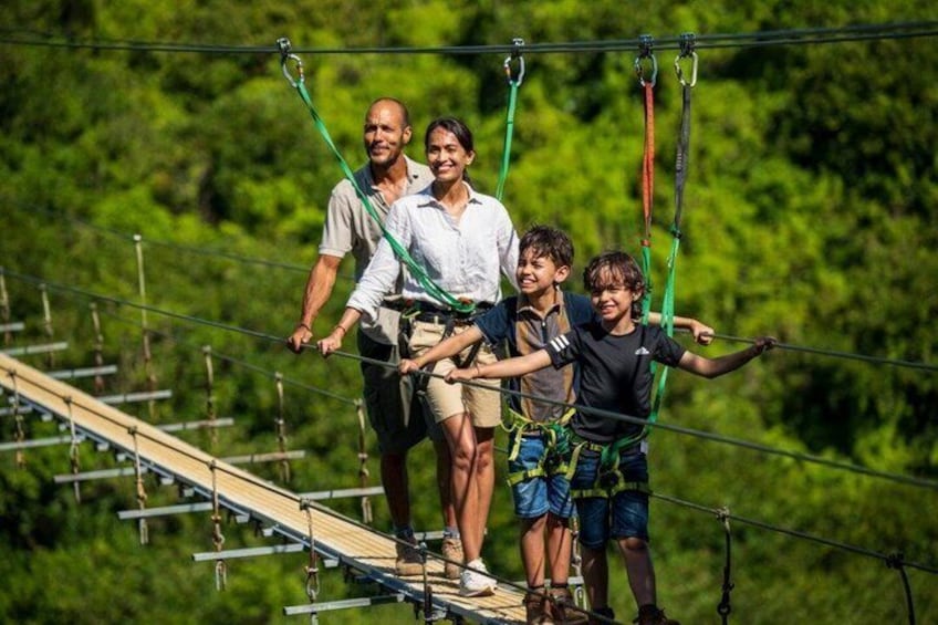 A group of people on a zip line course with safety harnesses, surrounded by greenery. 4