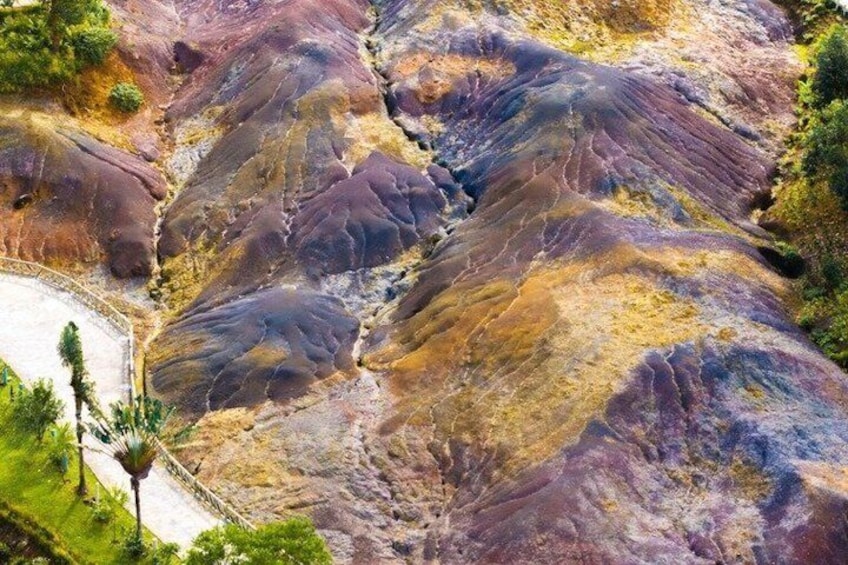 A rugged, multicolored rock formation with a winding path. 1